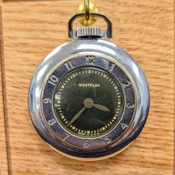 Front view of the Westclox open-face pocket watch showing the dark green dial, outer chapter ring, and chrome case
