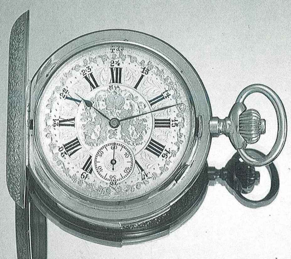 Front view showing the silver engine-turned dial with applied floral decoration, Roman numerals, outer 24-hour ring, and subsidiary seconds.