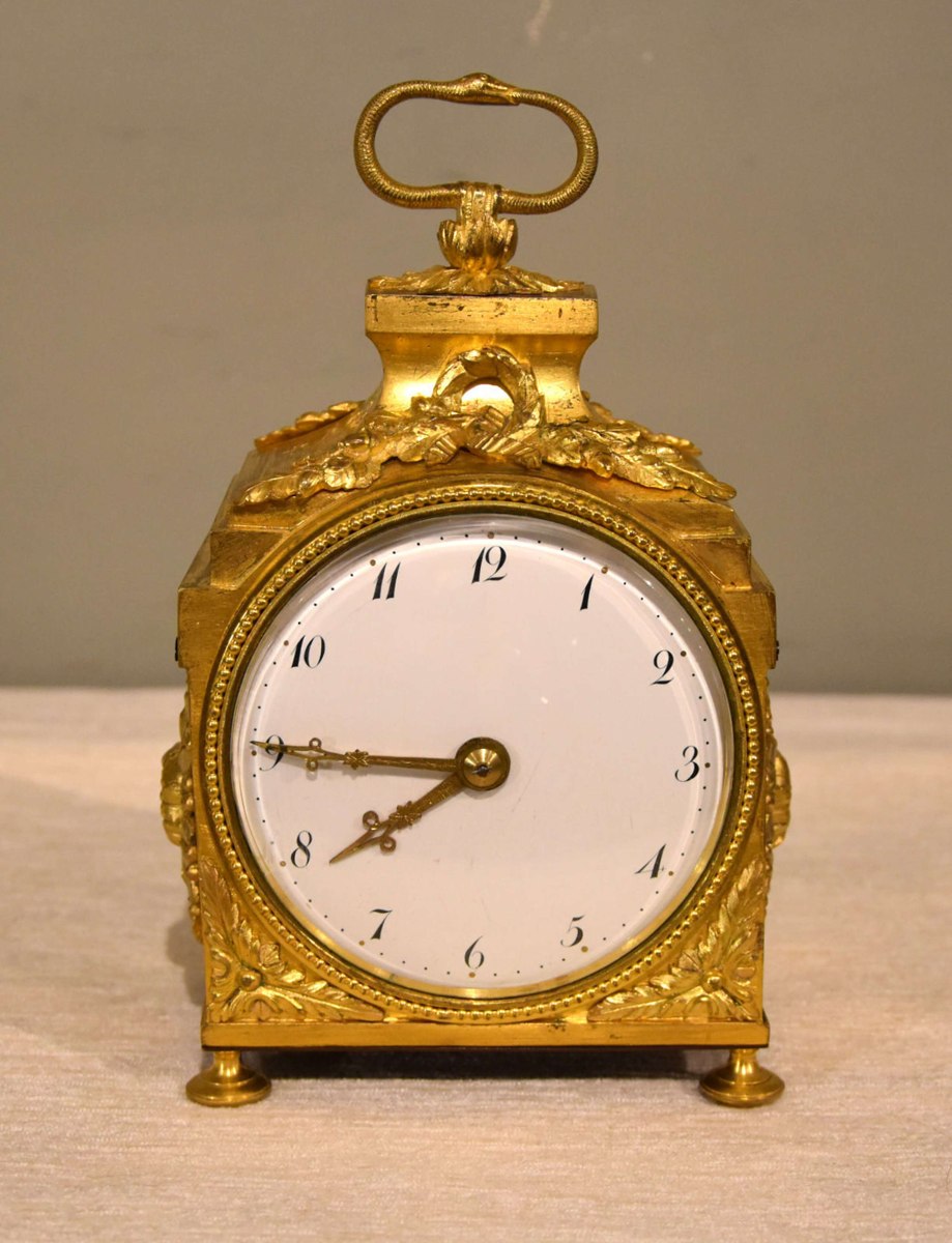 Front view of the gilded pendule d'officier showing the dial, bun feet, and snake handle