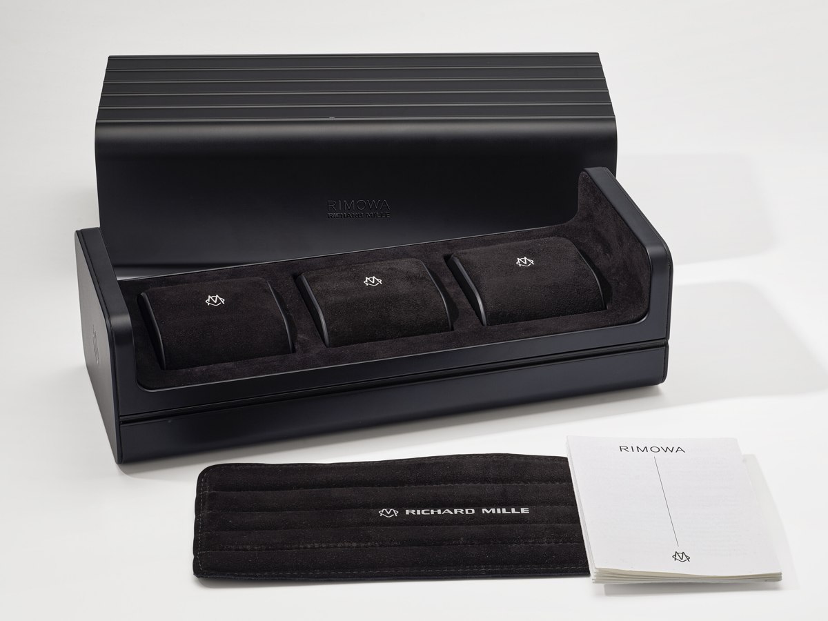 Open view of the Rimowa x Richard Mille black aluminum 3-watch box with cushions, pad, and booklet