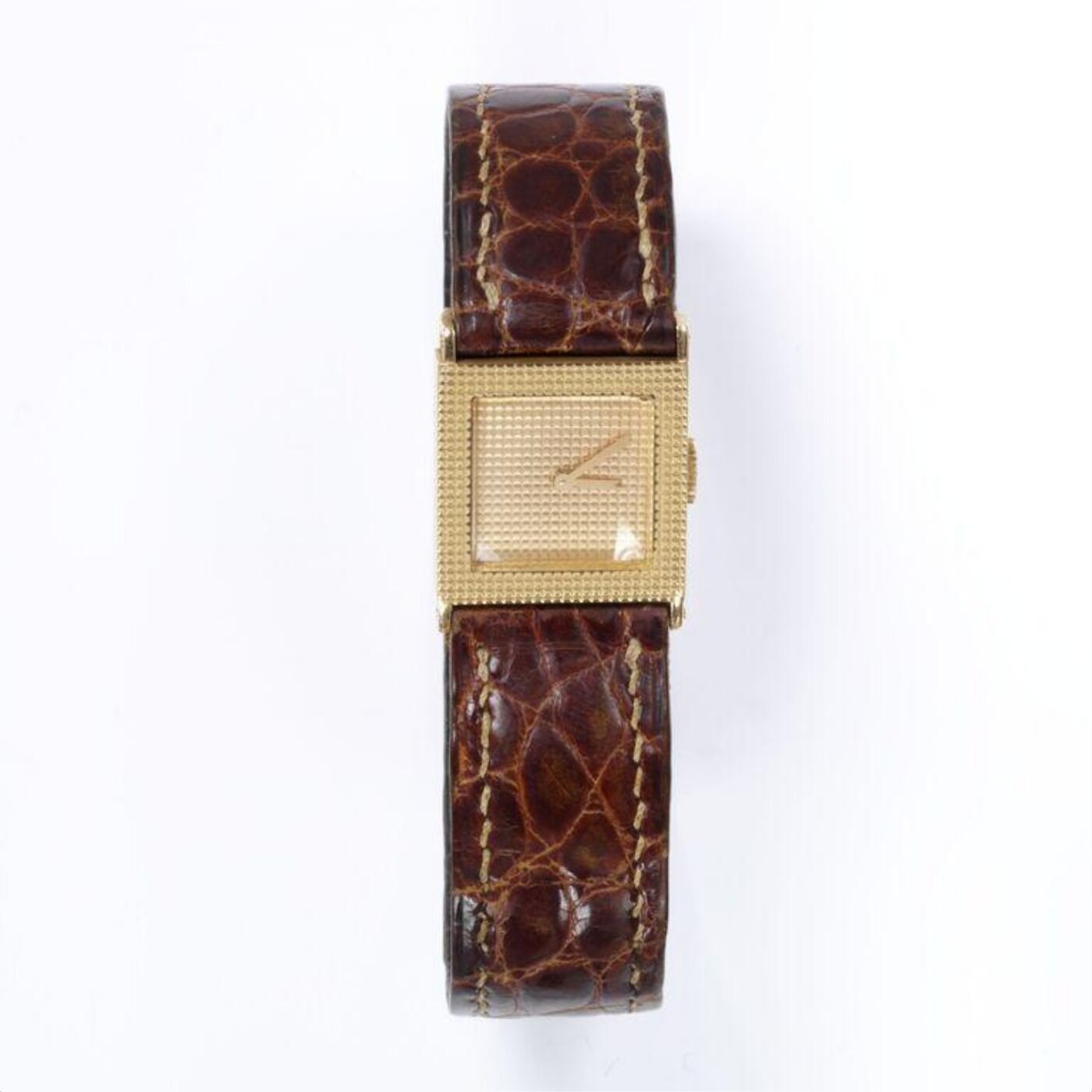Full view of the gold wristwatch, displaying the incised grid pattern on the square case and the attached leather strap.