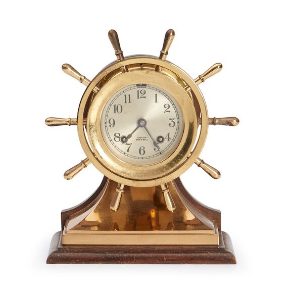 Front view of Chelsea ship's bell clock in brass wheel casing on plinth base