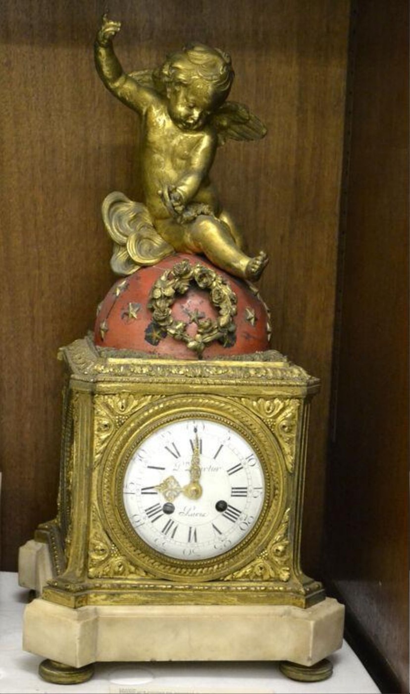 A spring-driven mantel clock featuring a cupid figurine, ormolu casing, and marble base.