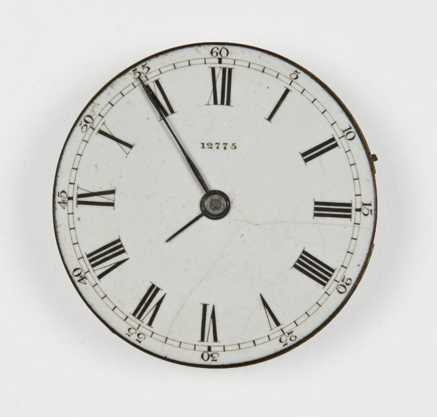 Front view of the repurposed metal watch dial showing the Roman numeral layout and central serial number.