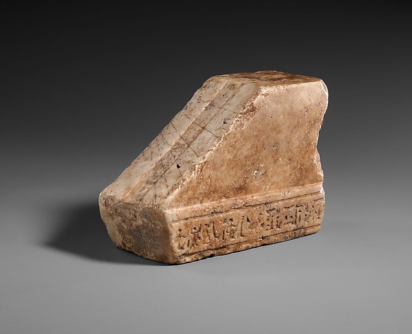 Marble shadow clock from the Ptolemaic period with an engraved sloping face for reading sun shadows.