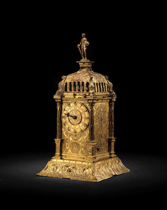 Three-quarter front view of the German gilt and engraved brass Augsburg tower clock showing the dial, arched colonnade, and Hercules finial
