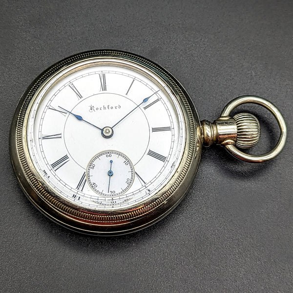 Front view of Rockford pocket watch showing white enamel dial, blued hands, and silverode case
