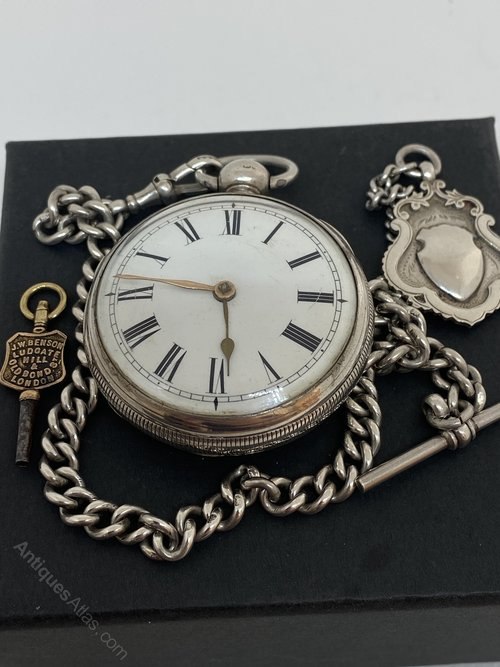 Dial view of the silver verge fusee pocket watch shown with its Albert chain, fob, and Benson key