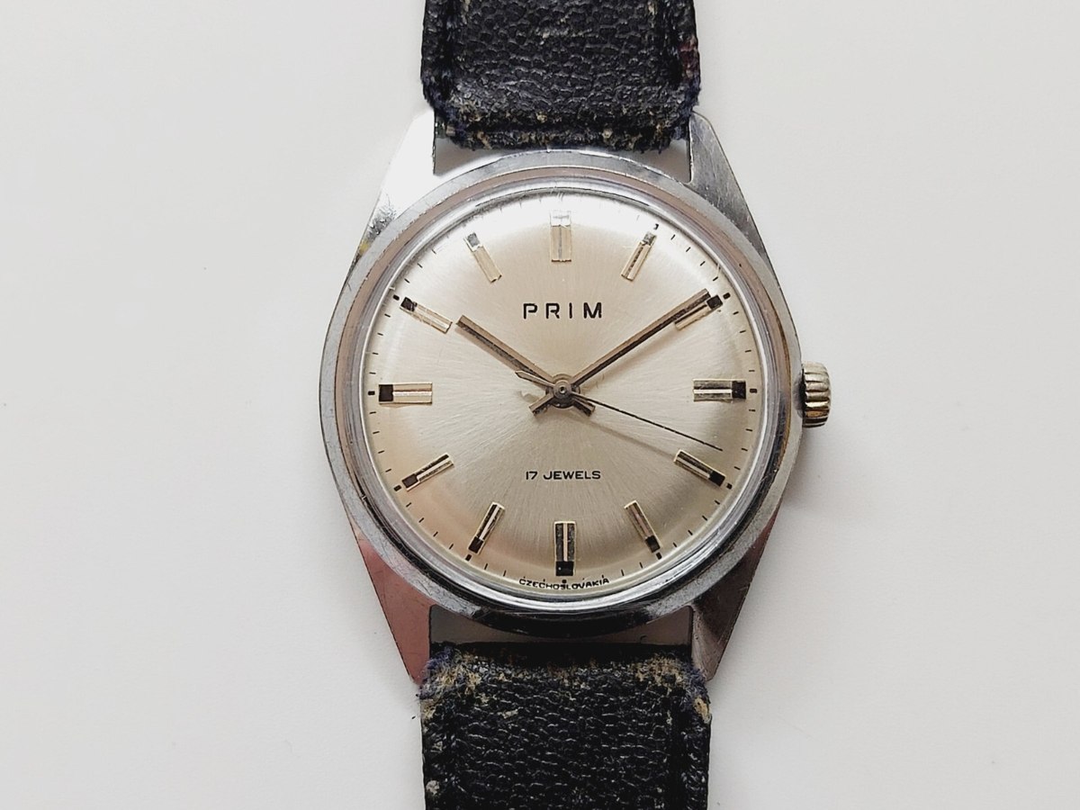 Dial and front view of the PRIM hand-winding wristwatch with black strap