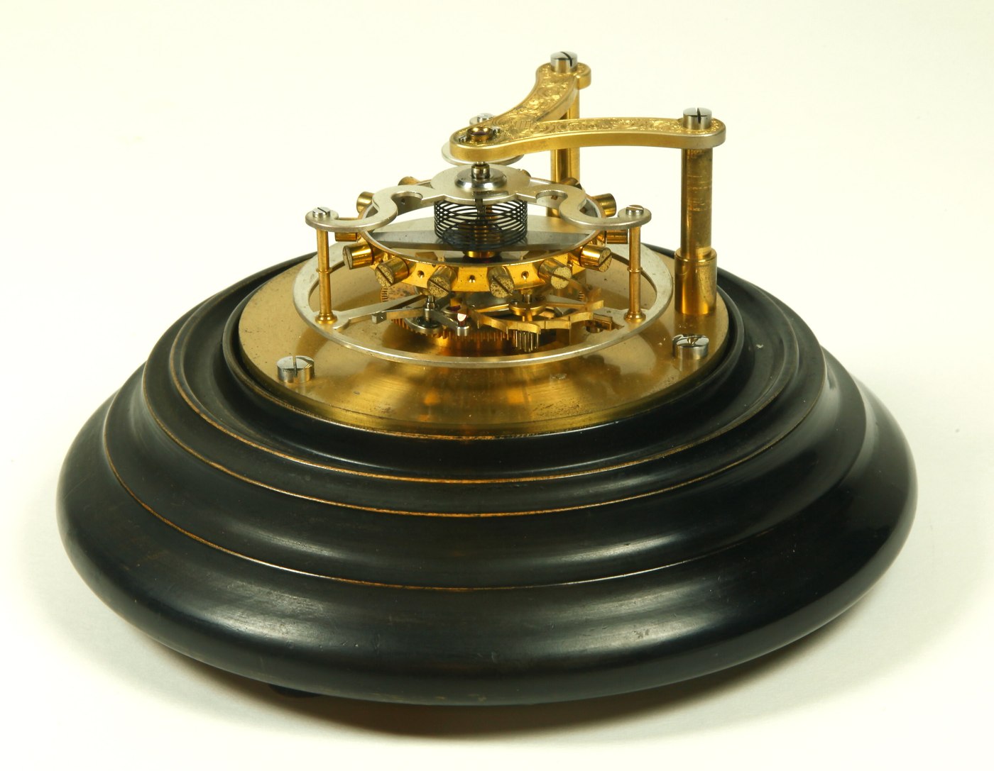 Side profile view showing the wooden base, vertical support pillars, and the chronometer escapement mechanism of the Earnshaw model.