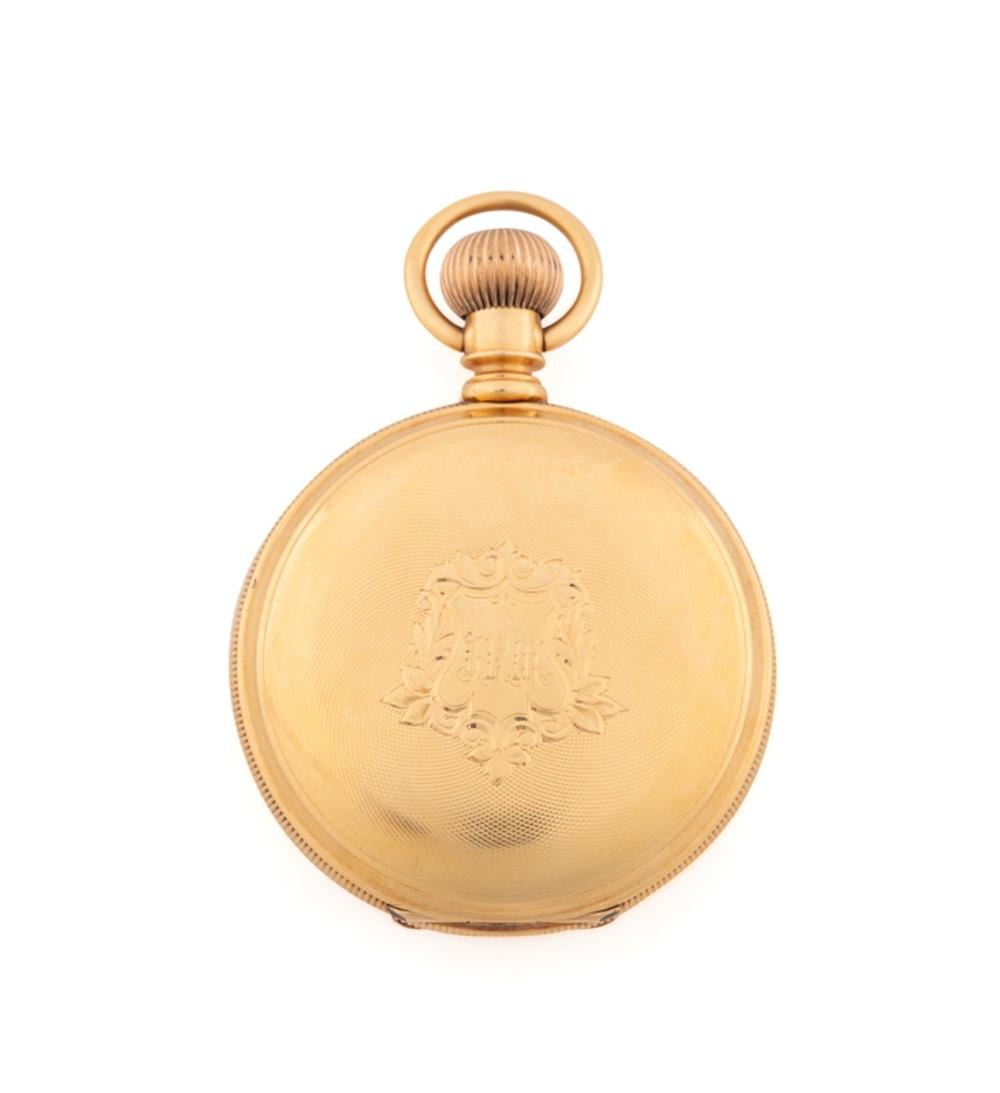Front exterior view of the closed gold hunter case pocket watch showing engraved shield and bow