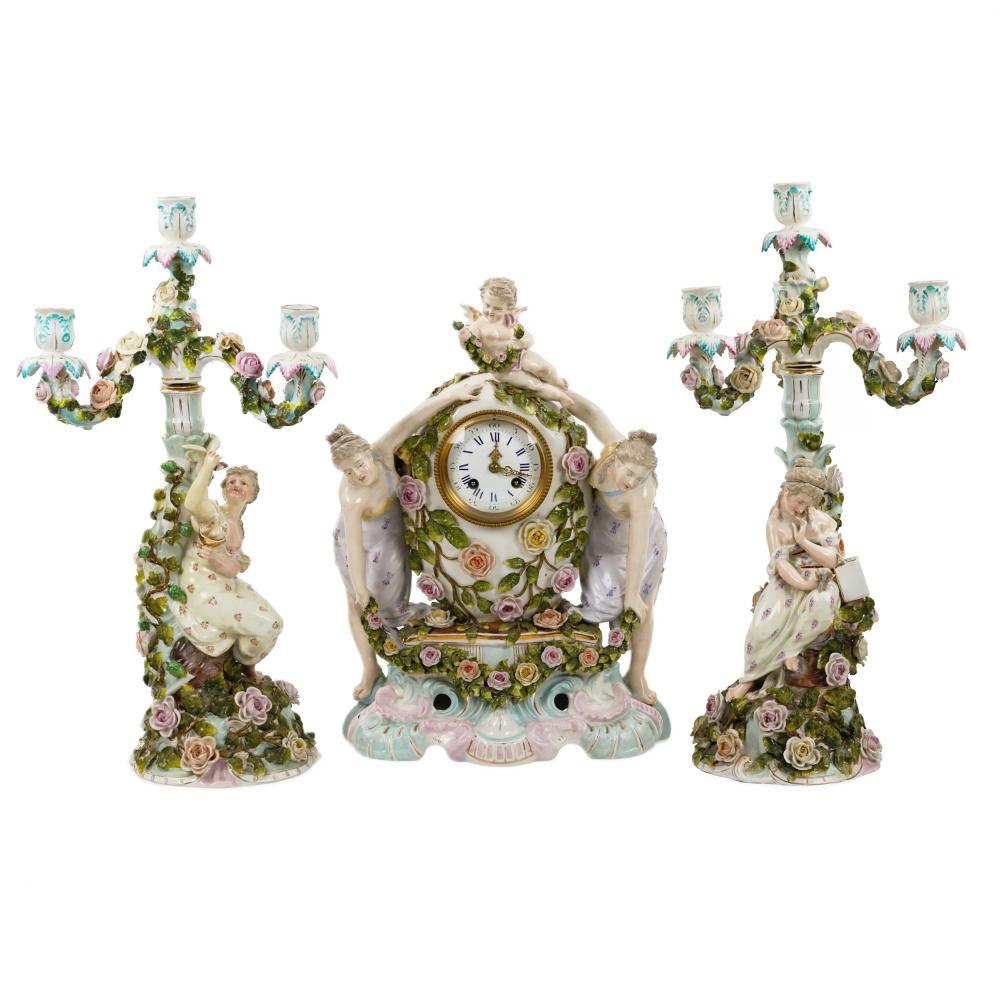 Sitzendorf porcelain clock set, consisting of a central clock flanked by two candelabra, featuring hand-modeled floral decorations and classical figures.