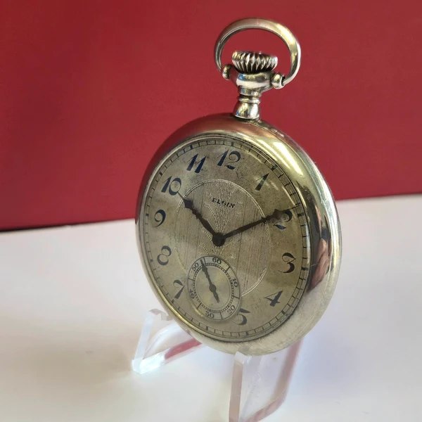 Three-quarter view of the Elgin openface pocket watch on an acrylic display stand