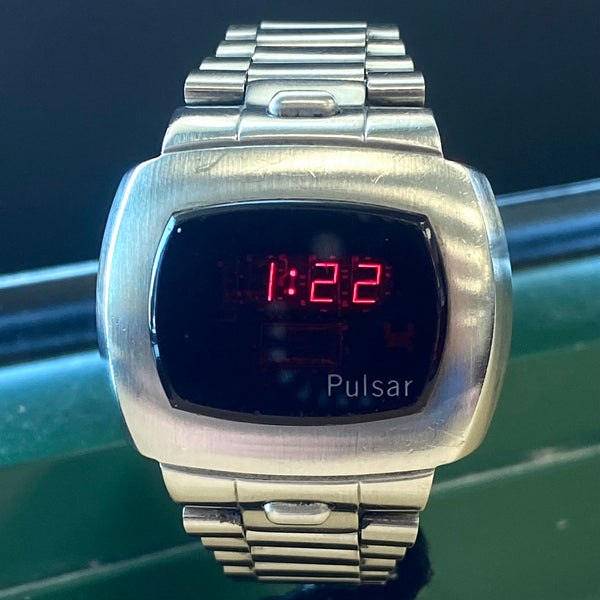 Front view of the Pulsar P4 digital wristwatch showing the brushed steel case, bracelet, and red LED time display reading 1:22