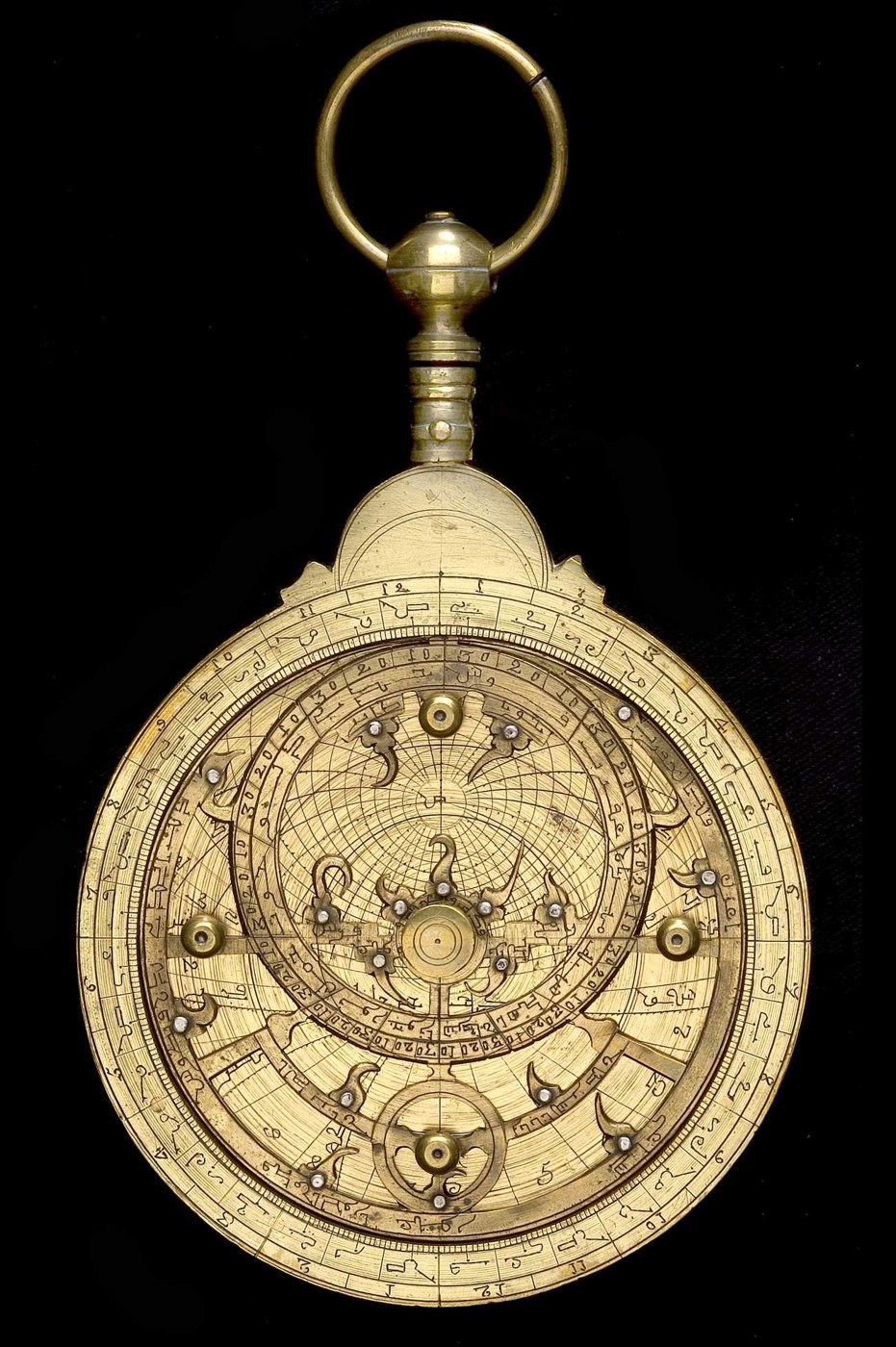 Front view of the North African brass astrolabe showing the rete, star pointers with silver studs, and the central pivot.