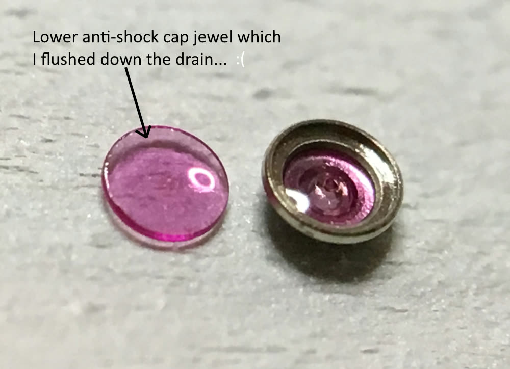 Two small endstone/bearing-setting components in a workshop photograph. Keep the cap jewel distinct from a pierced hole jewel; this is a repair discussion, not servicing authority.