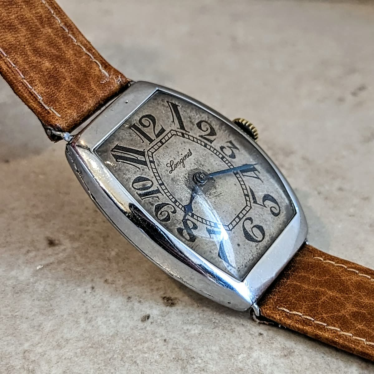 Oblique front view of the tonneau Longines wristwatch showing dial, curved case, and tan strap