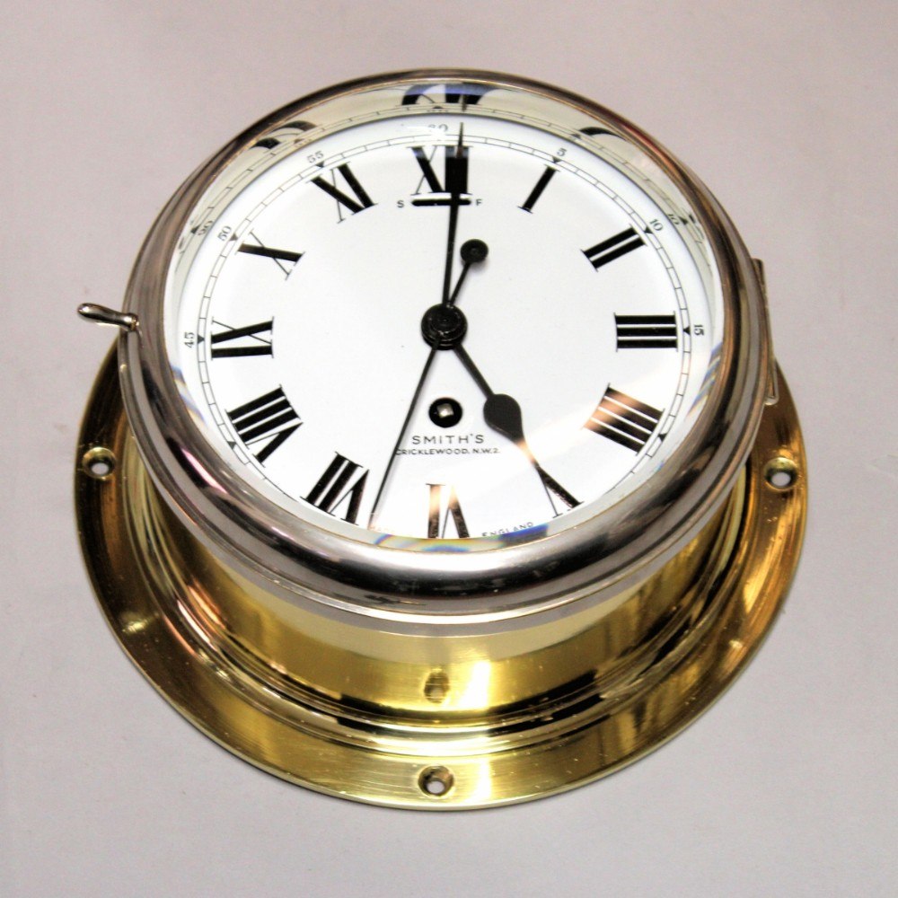 Oblique view showing the polished brass flange, chrome-plated bezel, and white enamel dial