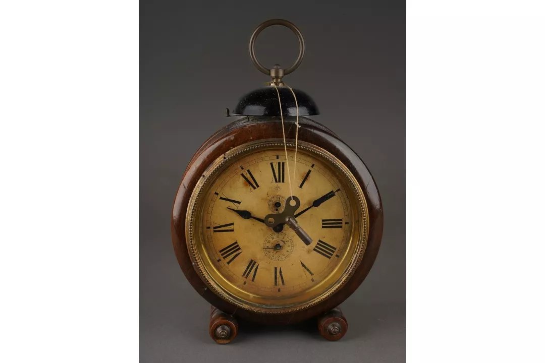 Front view of the Junghans drum-shaped walnut alarm clock with bell, carry handle, and suspended key