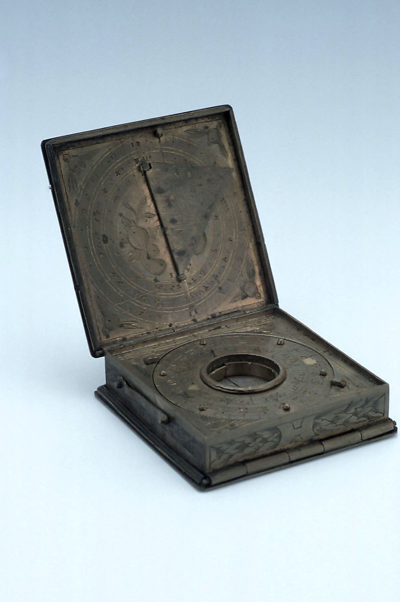 The astronomical compendium shown open, revealing the internal dial scales, the compass housing, and the folding gnomon.