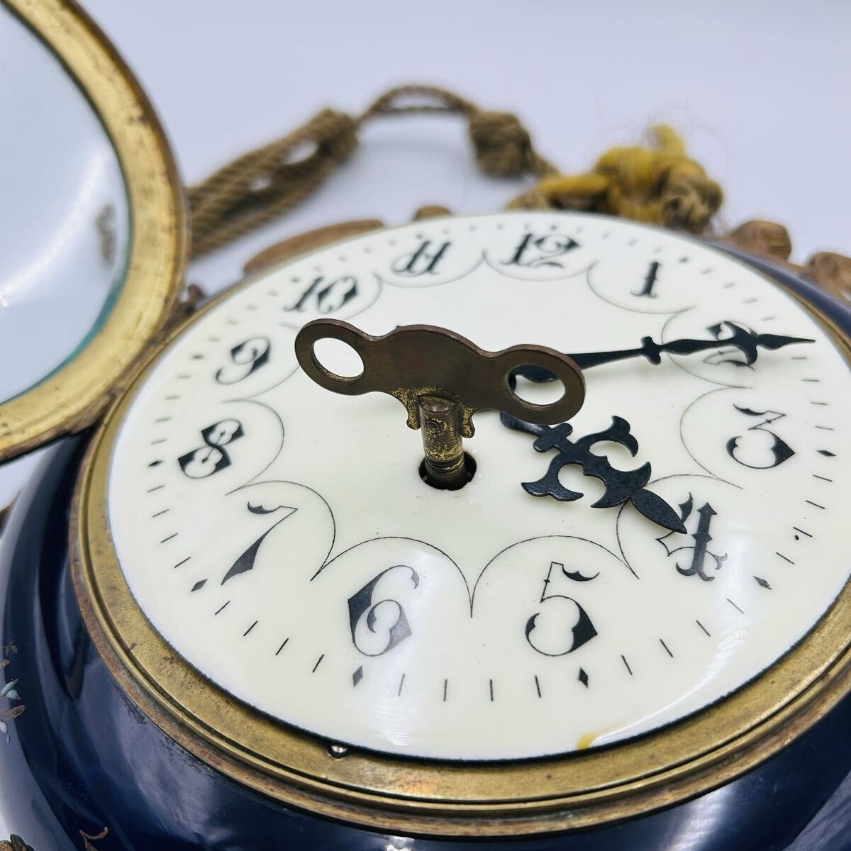 Oblique view of the clock dial with hinged bezel opened and winding key in place