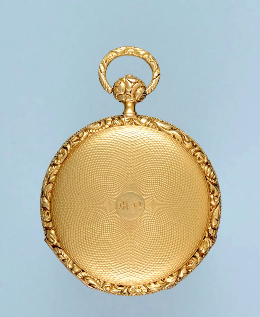 Rear view of the 18-carat gold case showing engine turning, central monogram cartouche, and chased floral border