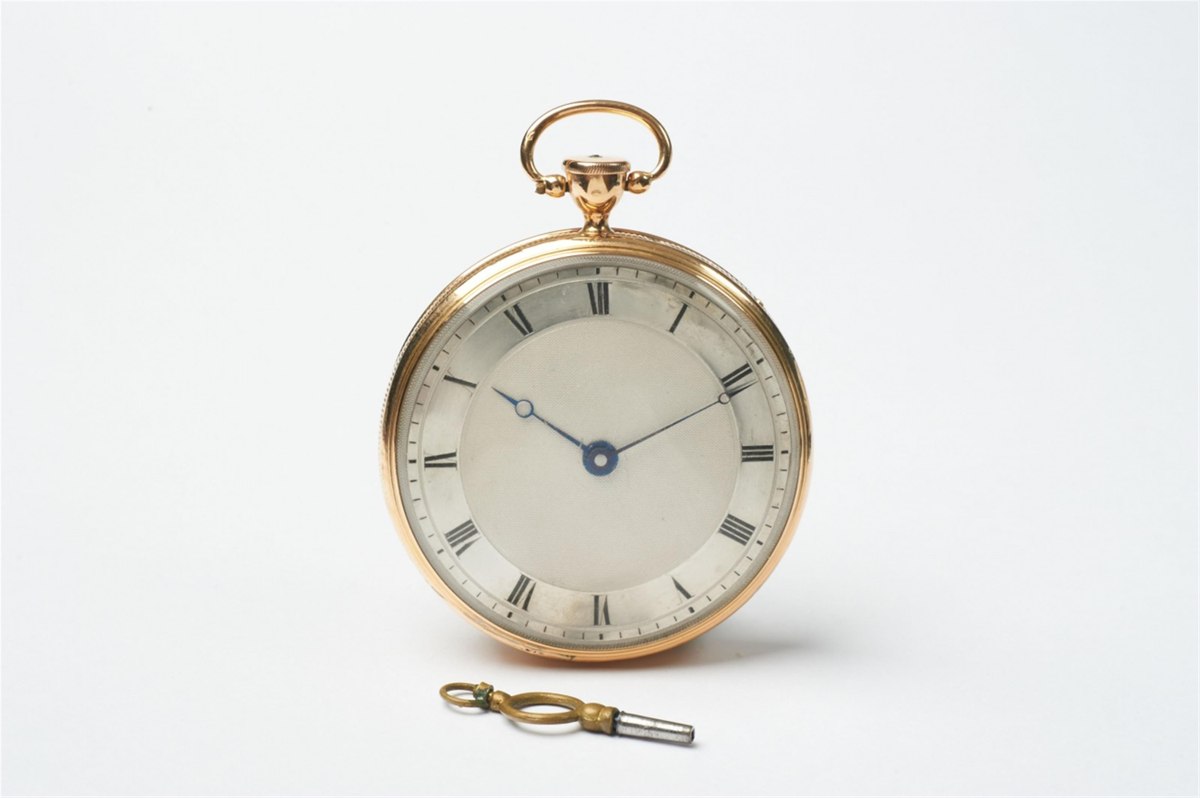 Dial view of the Swiss 18k gold openface musical pocket watch shown with winding key