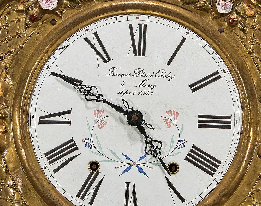 Close-up view of the dial and ornate gilt surround of the wall clock