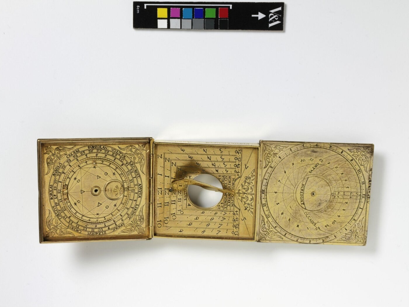 An open astronomical compendium in gilt copper, featuring a sundial and celestial tables, dated 1557.