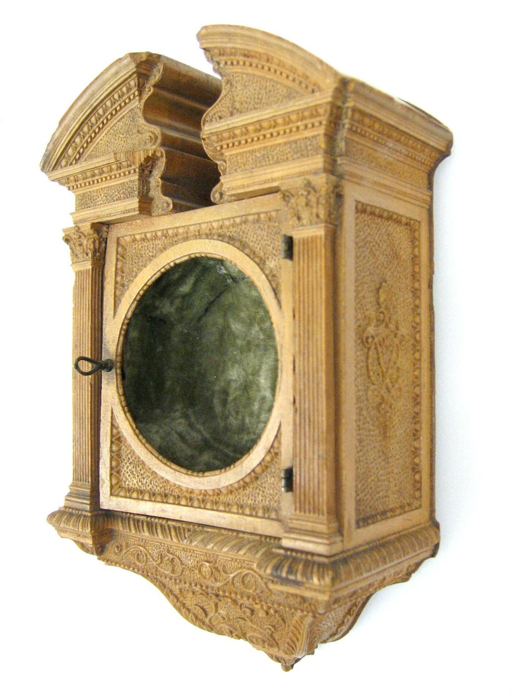A side-angle view of the carved boxwood watch case, displaying the hinged door, circular aperture, and the Corinthian pilasters.