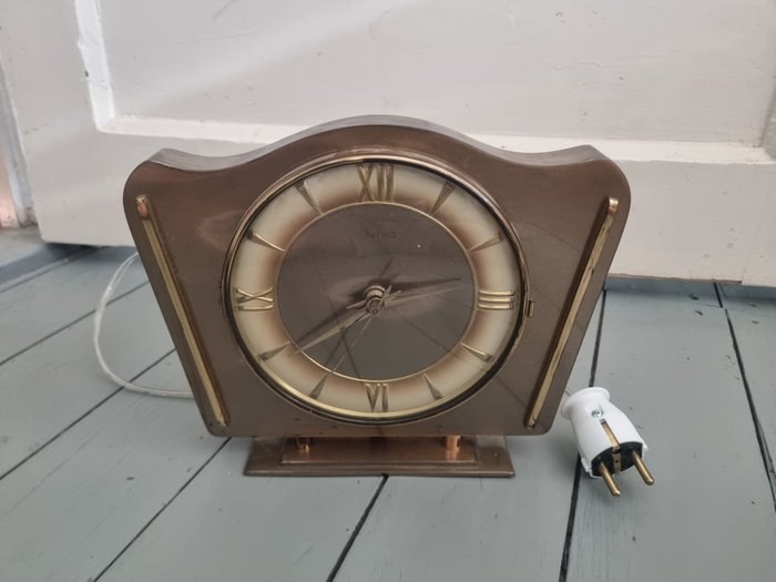Front view of the Hesma electric clock showing dial, case, and power plug