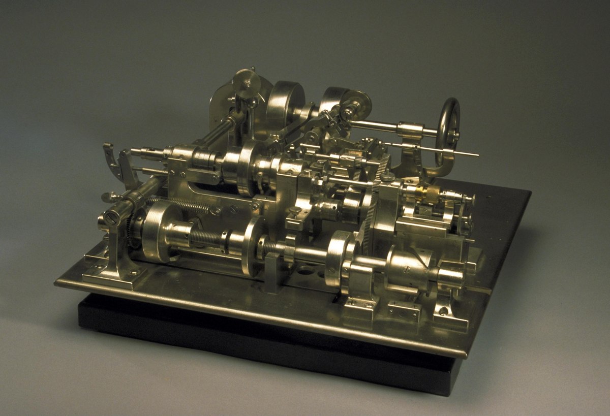 Three-quarter elevated perspective of the nickel-plated automatic screw making machine on its mounting base.