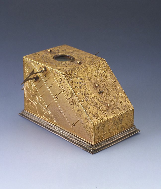 The polyhedral sundial showing the upper face with the compass recess and the side faces with engraved cherubim and dial markings.
