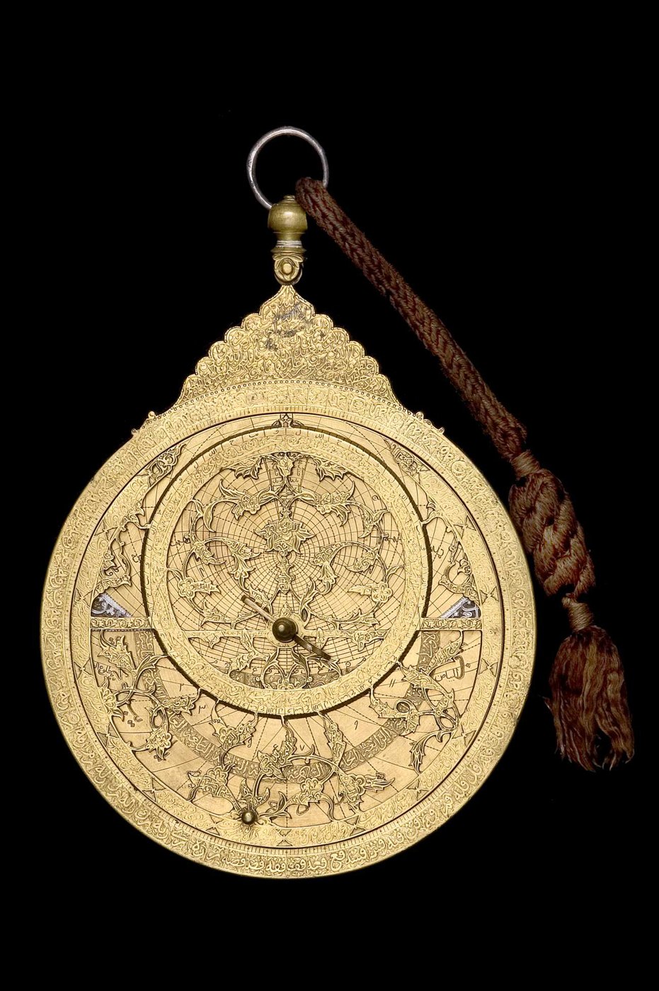Full view of the astrolabe, showing the intricate foliate rete and the suspension shackle, with a brown braided cord attached.