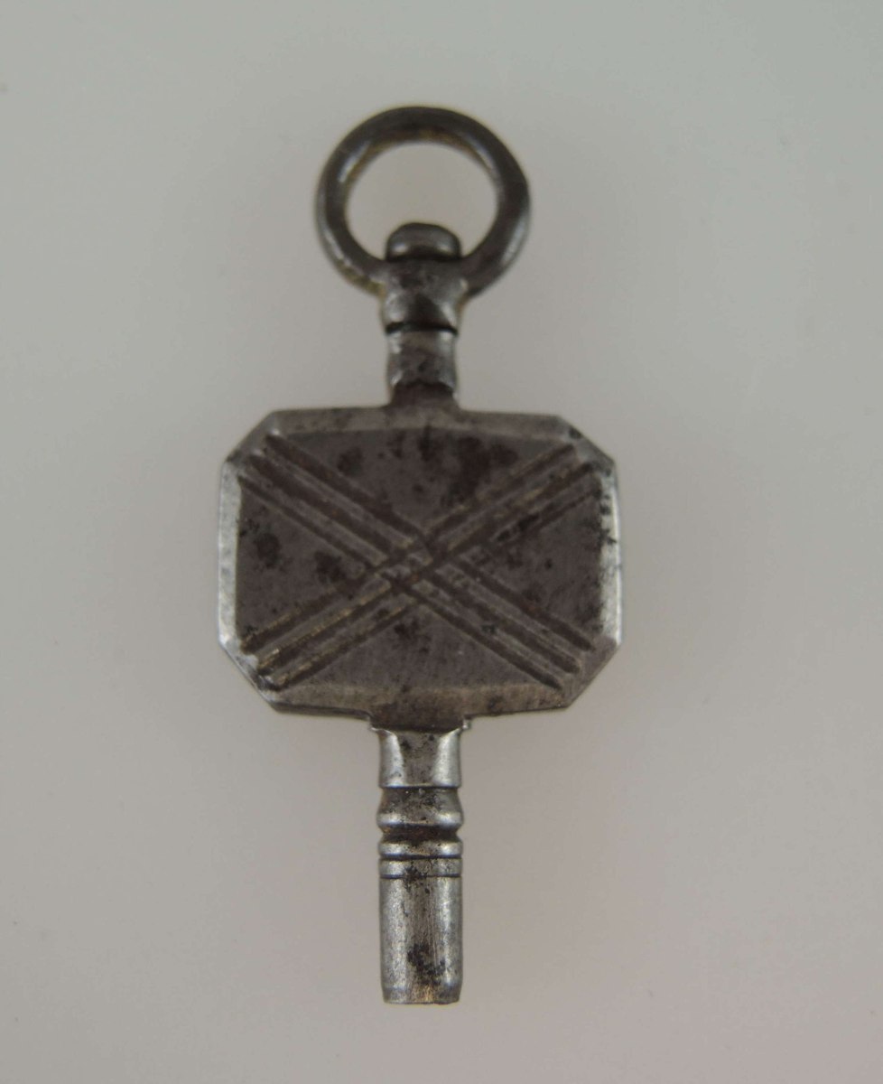 Steel pocket watch key with engraved X pattern, suspension ring, and turned pipe