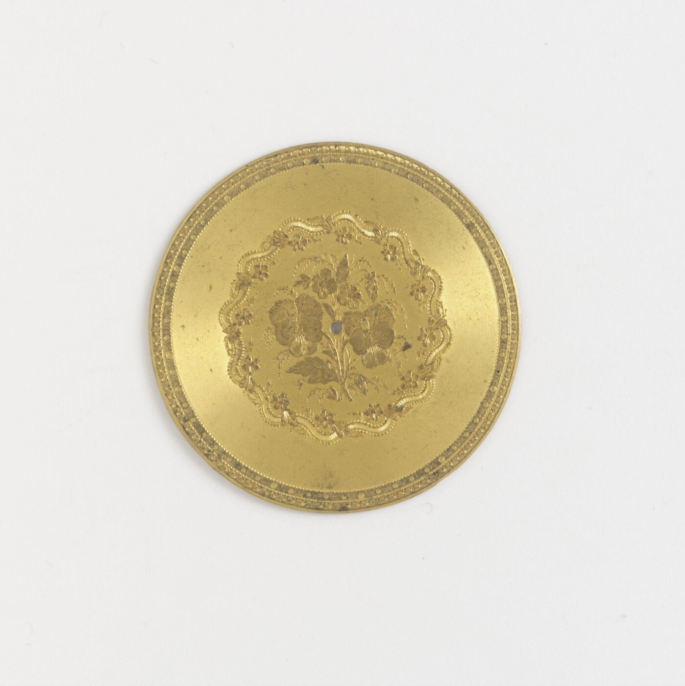 Gilt metal watch dial with floral engraving and no numerals, 1850-1880.