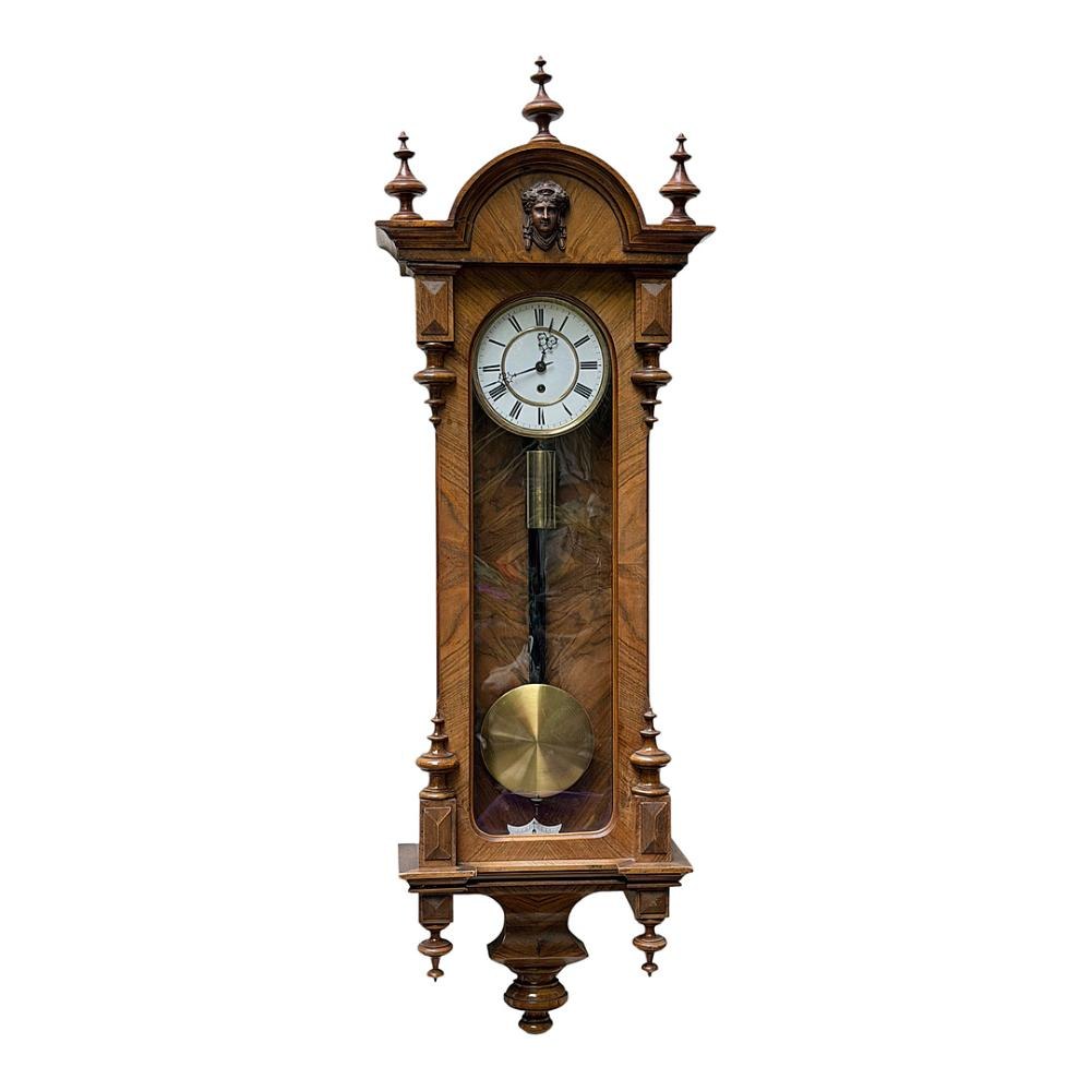Front view of the walnut wall regulator showing the case carving, dial, weight, and pendulum