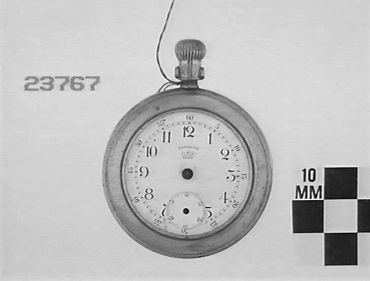 The obverse side of the Waterbury Watch Co. pocket watch showing the white enamel dial and sub-seconds dial, with missing hands and the winding stem at the top.