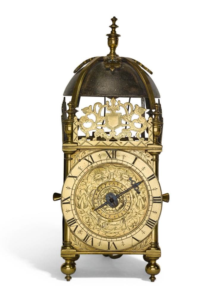 Front view of the brass lantern clock showing the engraved dial, pierced fret, and bell assembly