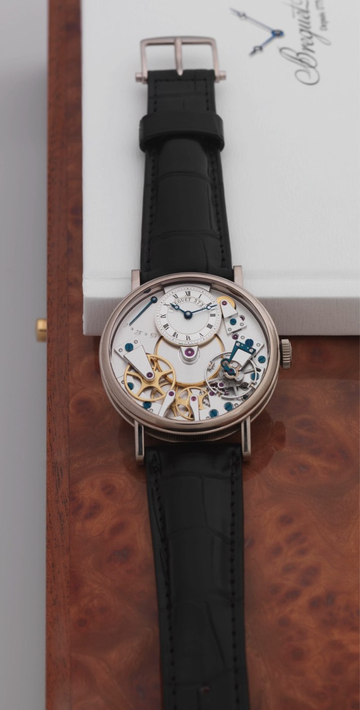 Frontal view of the Breguet Tradition watch showing the open movement, off-center dial, and black leather strap.