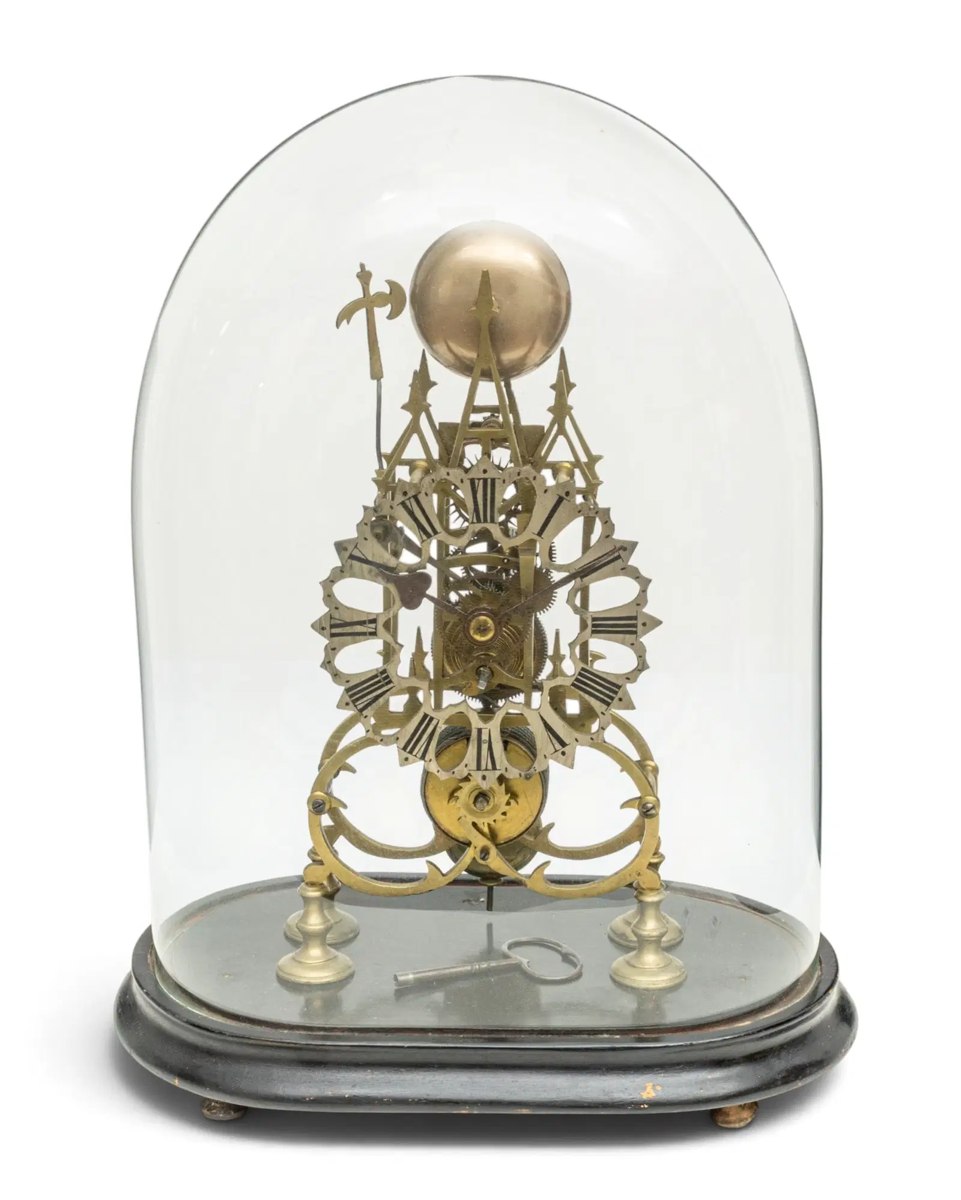 Front view of nineteenth-century brass skeleton clock under an oval glass dome
