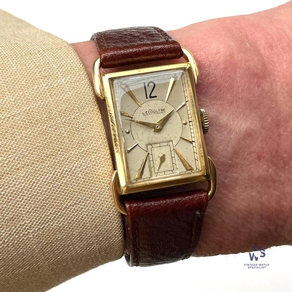 Wrist view of the rectangular LeCoultre dress watch showing the dial, hands, and looped lugs