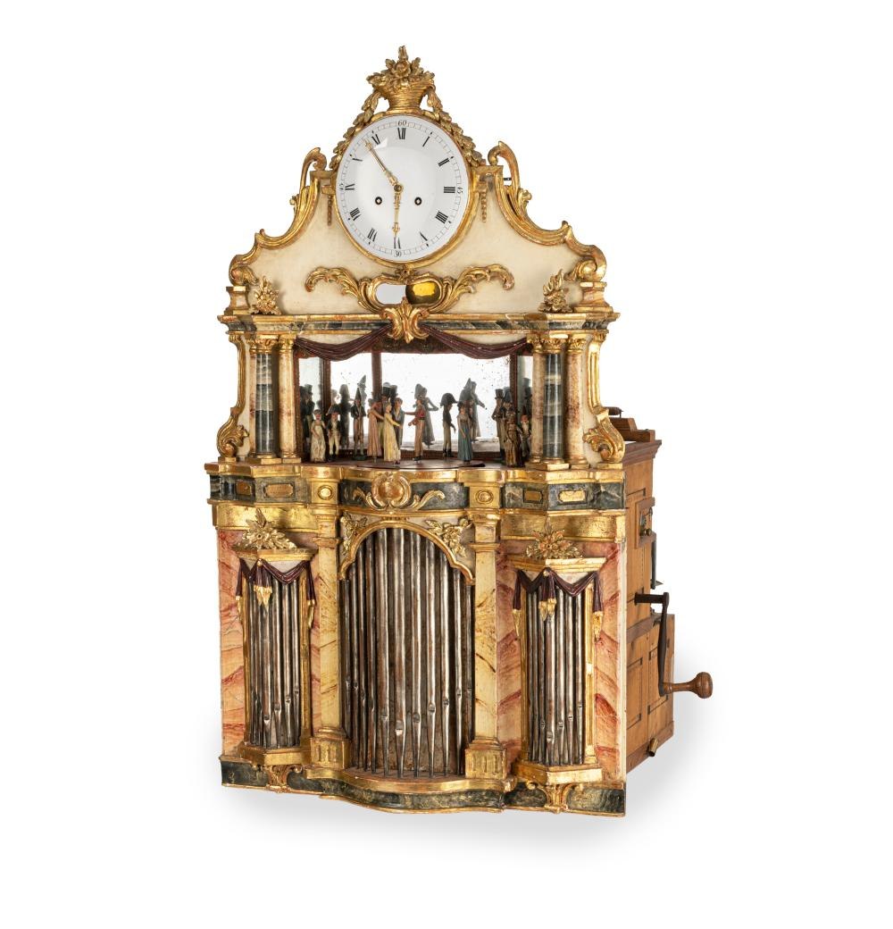 Frontal view of the large Black Forest flute clock showing the theatre backdrop and organ pipe decoration.