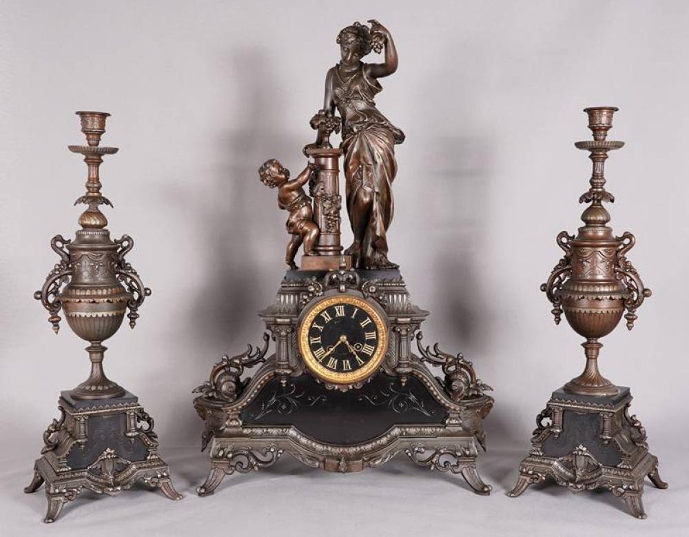 The mantel clock set, comprising a central clock with a figurative top and two matching side amphorae.