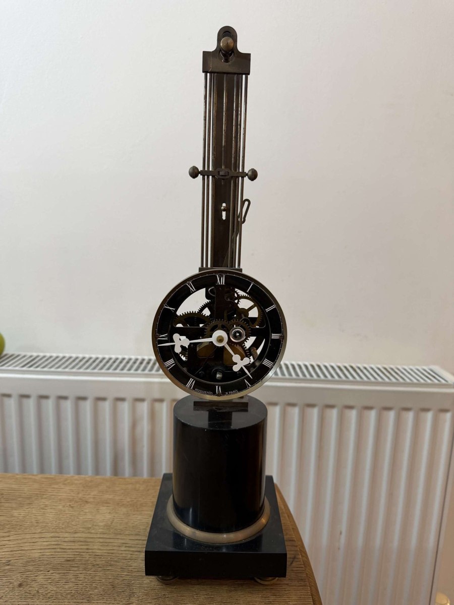Front view of the mystery skeleton swinging clock on its dark plinth base