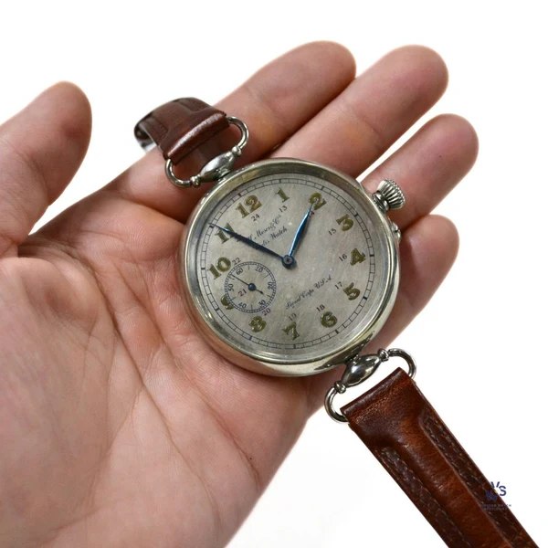Oblique dial view of the oversized converted wristwatch held in hand, showing blued hands and sub-seconds at 9 o'clock