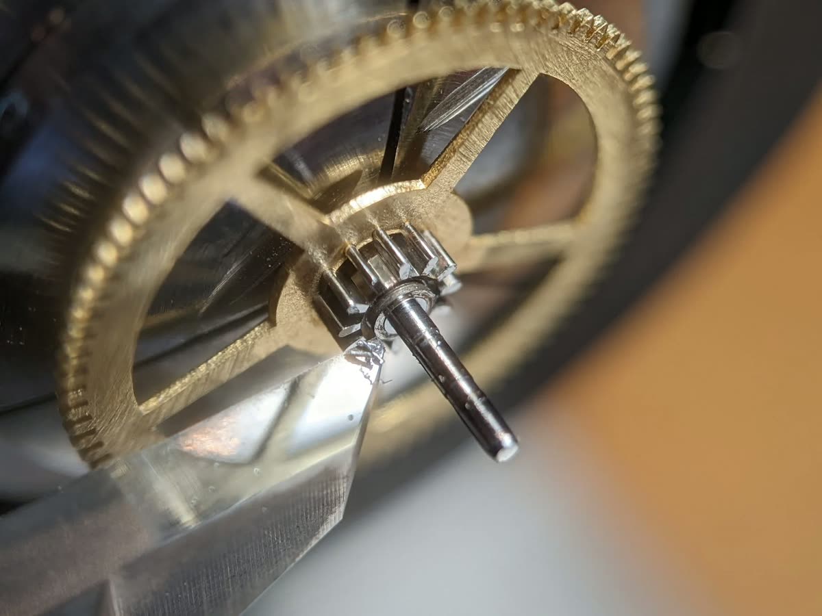 A centre wheel and its arbor in a repair close-up. The source discusses wear; this is not a pristine reference specimen or a guide to repairing it yourself.