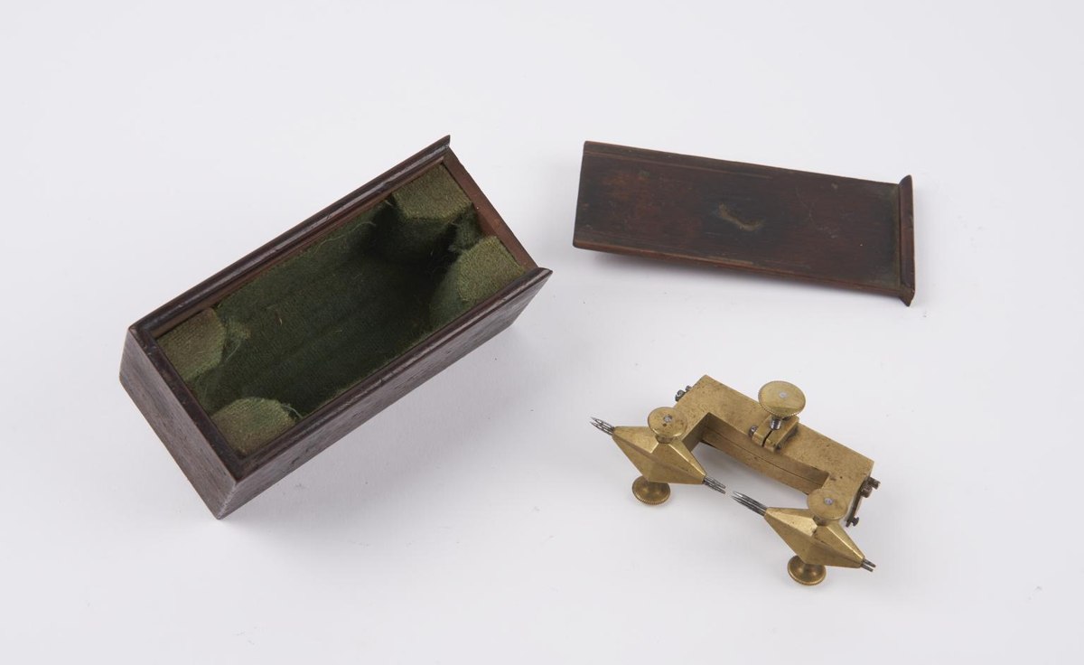 Brass depthing tool shown beside its green-lined wooden slide-lid box