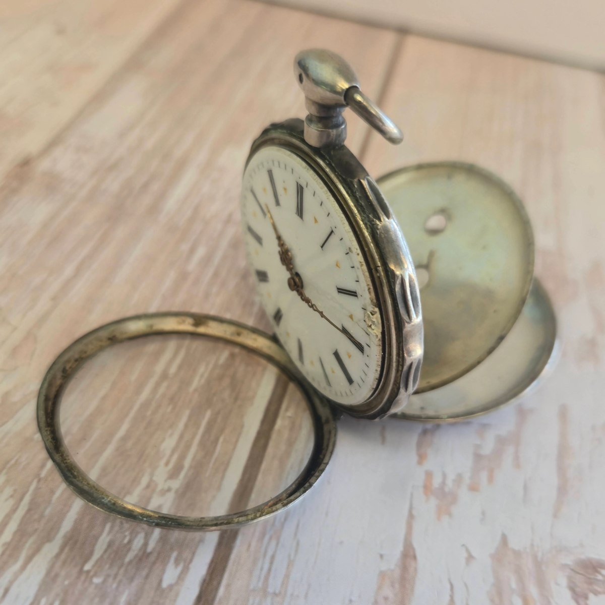 Oblique view of the open-face pocket watch showing the white Roman numeral dial, hinged front bezel, and opened cuvettes