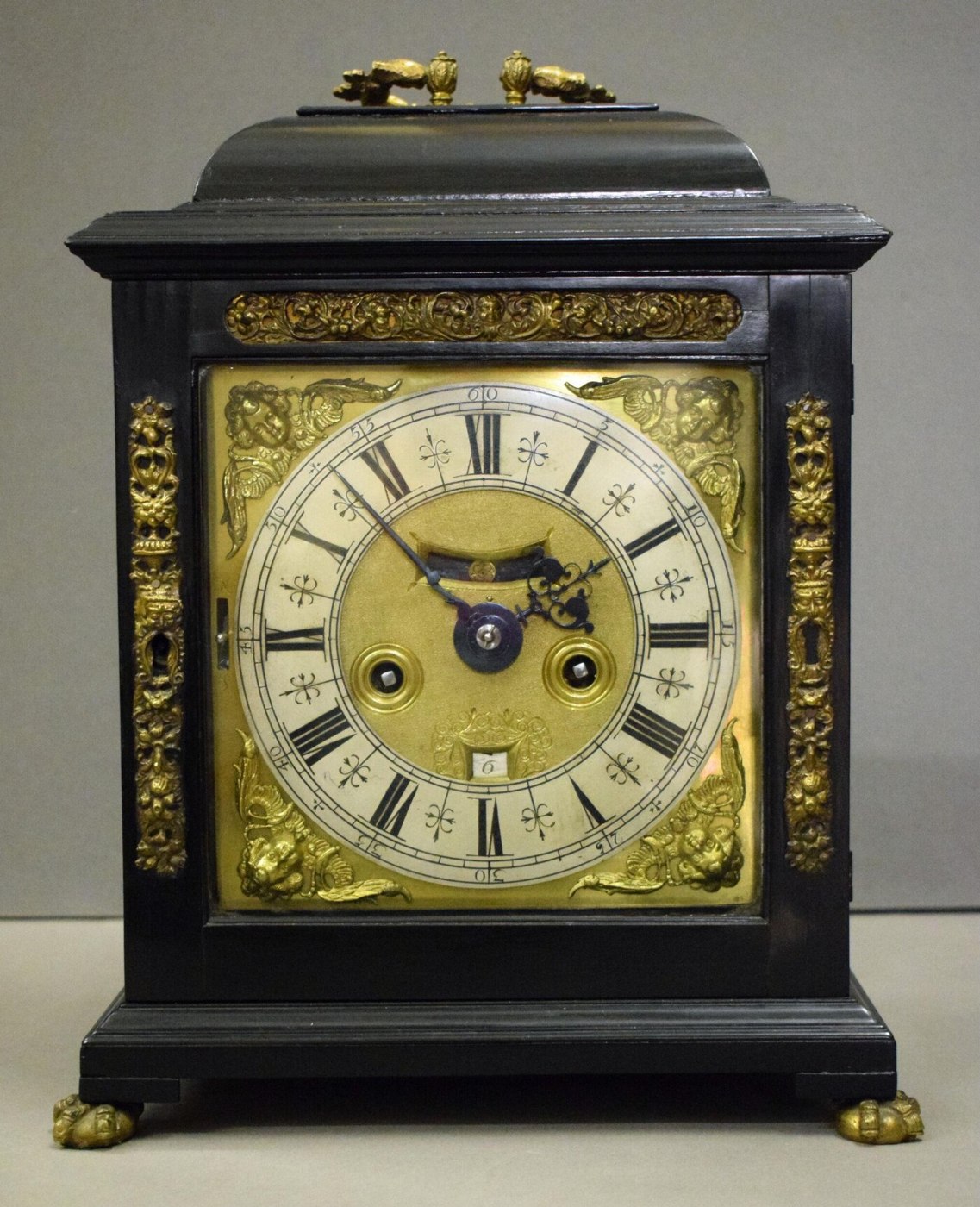 Front view of the bracket clock by Charles Gretton, showing the brass dial and cherub spandrels.